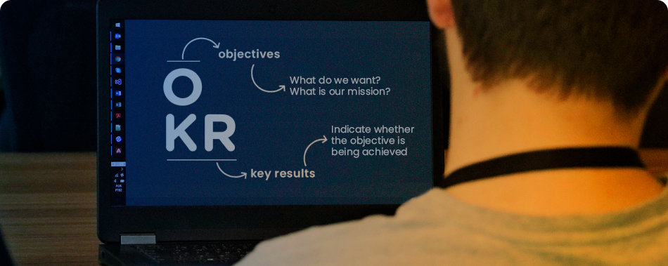 OKR acronym on a notebook screen. From the letter O come the words objectives and the questions 