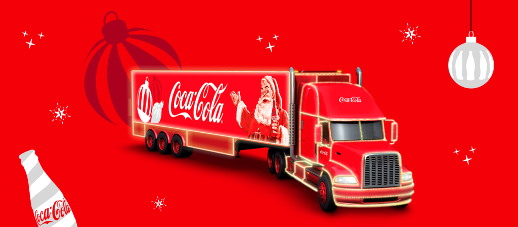 Um caminhão iluminado com luzes de Natal e ilustração de Papai Noel, com o logotipo da Coca-Cola, aparece sobre um fundo vermelho.