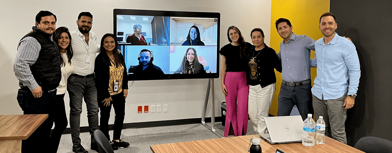 Photo of DLL employees around a television showing a video conference.