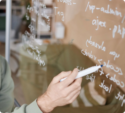 Photo of man writing on glass board with white pen.