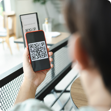 Um homem segura um smartphone com um QR Code na tela.