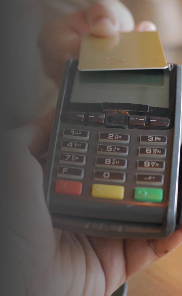 Person making a contactless payment with a gold card on a credit card machine.