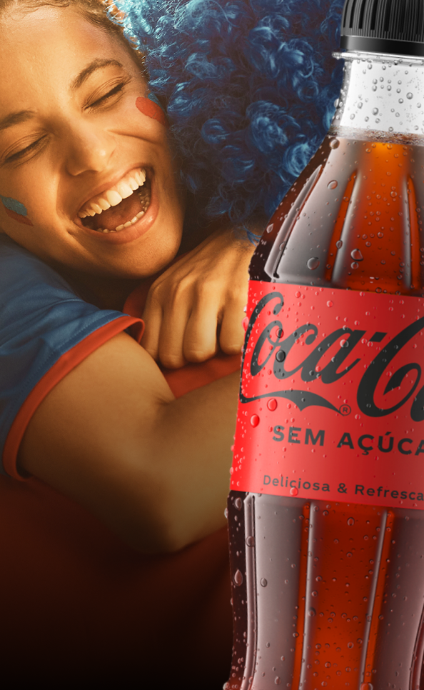 Pessoa sorridente abraçando alguém com peruca azul. Garrafa de Coca-Cola Sem Açúcar.