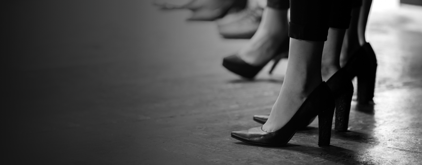 A imagem mostra pés femininos com sapatos pretos.