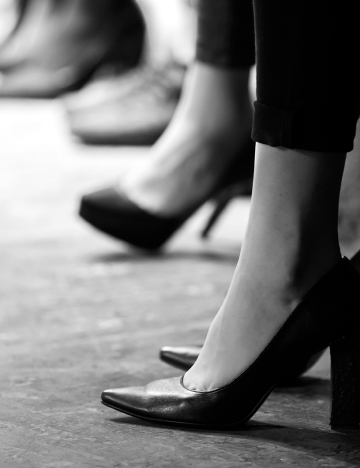A imagem mostra pés femininos com sapatos pretos.