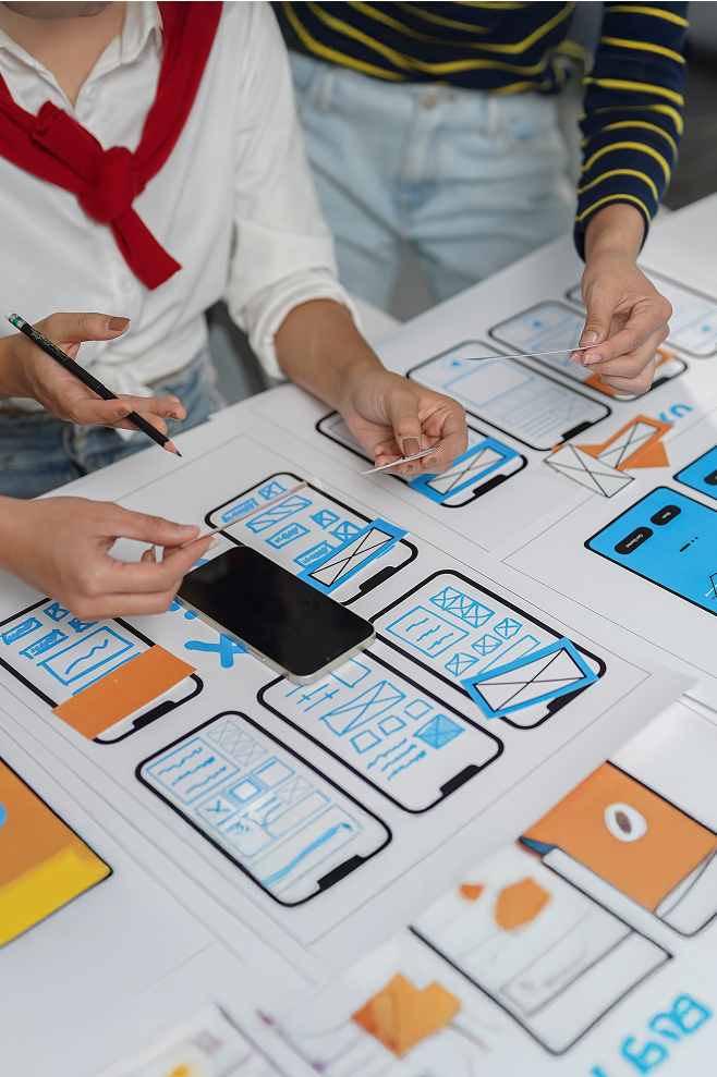Wireframes de aplicativo de celular e mãos de pessoas no entorno.