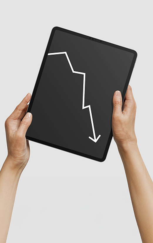Mãos seguram um tablet exibindo um gráfico em queda com seta apontando para baixo.