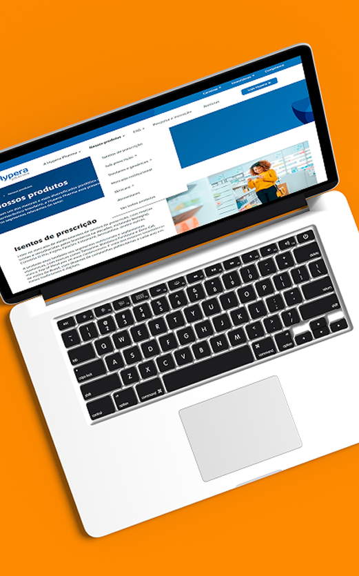 Notebook aberto exibindo um site corporativo sobre produtos, sobre fundo laranja vibrante.