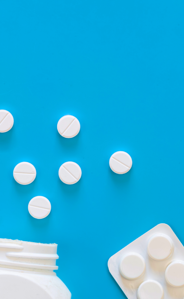 Comprimidos brancos espalhados sobre fundo azul com frasco e blister.