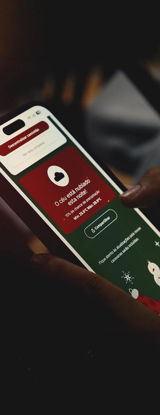 Pessoa segurando um smartphone com a tela ligada, exibindo um aplicativo de previsão do tempo. Na interface, aparece a mensagem “O céu está nublado esta noite”, com informações adicionais e um botão de compartilhar. A imagem tem iluminação baixa, com foco no celular e fundo desfocado.